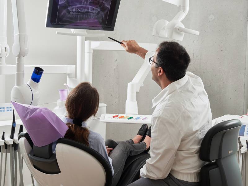 A man and a woman sitting in a dental chair, receiving a root canal examination from a dentist in Gold Coast.