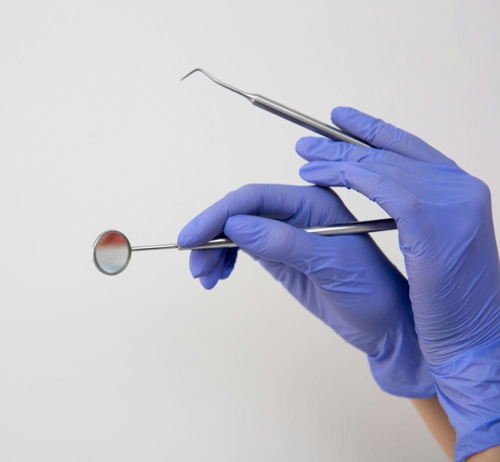 A person wearing blue gloves holds a toothbrush, preparing to address a toothache with dental care.